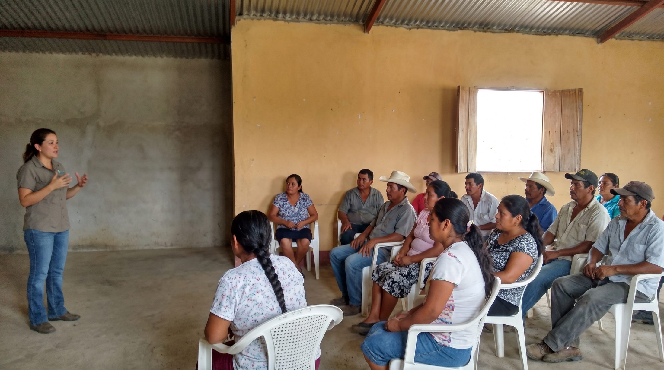 Facilitadora dando un taller comunitario de finanzas a un grupo numeroso en una zona rural de América Latina